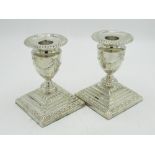 Pair of Geo.V hallmarked sterling silver candlesticks, urn shaped sconces relief decorated with bows