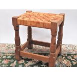 Robert Mouseman Thompson of Kilburn - an oak rectangular stool, plaited leather top on octagonal