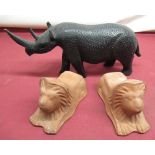 Ebonised wooden model of a rhino and two terracotta lion figures (3)