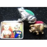 Brass pig pincushion, silver pill box with enamel lid depicting royal cats, and a silver pin cushion