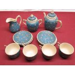 Cloisonne on porcelain four person tea service decorated with foliage and butterflies on a blue