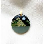 Green hardstone circular pendant with geometric pieces creating stylised landscape with opal moon,