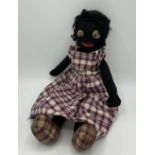 Mid C20th golly doll with leather eyes and mouth, wearing a plaid dress and shoes