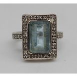 9ct white gold ring set with emerald cut aquamarine, surrounded by diamonds in millegrain setting,