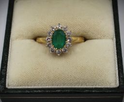 18ct yellow gold diamond and emerald cluster ring, the central oval cut emerald surrounded by a halo