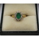 18ct yellow gold diamond and emerald cluster ring, the central oval cut emerald surrounded by a halo