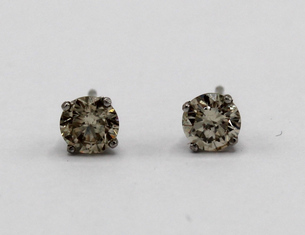 Pair of 14ct white gold solitaire diamond stud earrings, stamped 14ct, with silver butterfly backs