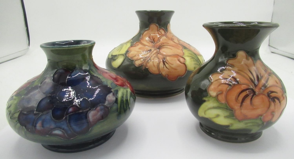 Moorcroft vase decorated with pink flowers on a green ground, similar smaller vase, another with