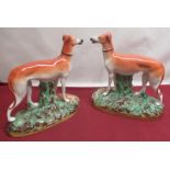 Pair of Staffordshire models of standing Hounds with fallen game, on naturalistic oval bases,