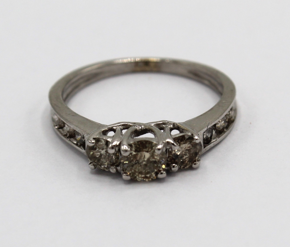 White gold diamond ring, the three central round cut diamonds set on a half eternity band, stamped