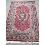 Persian pattern red ground wool rug, stepped medallion centre with scrolled foliage, stylised