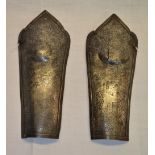 Pair of Indo-Persian c.C17th iron lower leg guards with engraved detail of fighting figures with