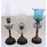 Three early C20th oil lamps on black terracotta bases with brass columns (one missing shade and