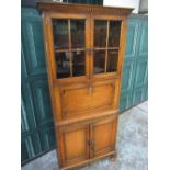 C20th oak side cabinet, two glazed doors and fall front with fitted interior above two doors, on bun