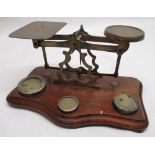 Early C20th brass postage scales pierced and shaped centre on shaped and moulded mahogany base W23cm