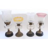 Four squat early C20th oil lamps with clear glass reservoirs and two later glass shades (no