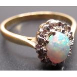 yellow metal opal and diamond ring, the central oval opal surrounded by a halo of diamonds,