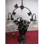Cast metal figural three light table lamp of two cherubic figures on ebonized base, indistinctly