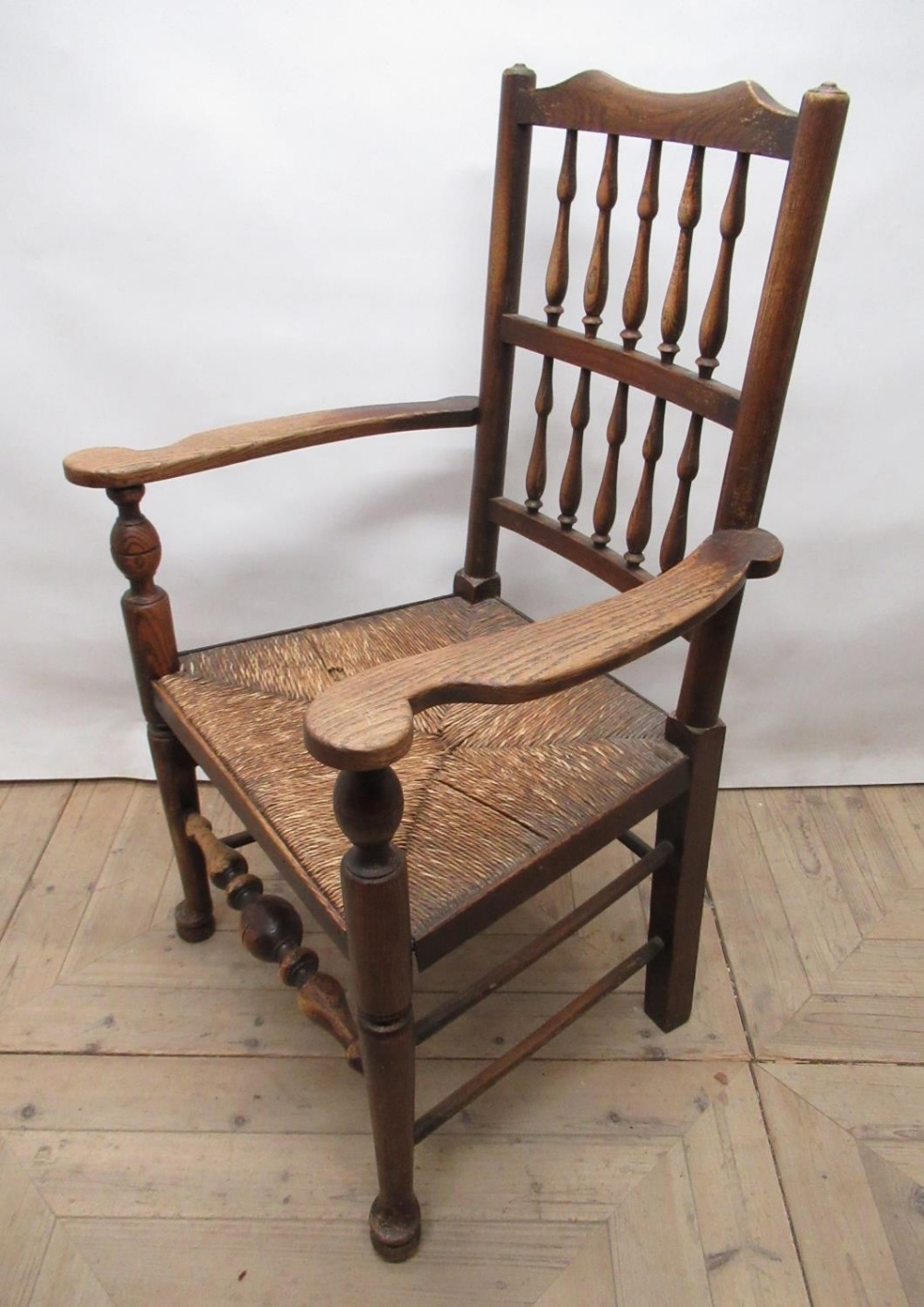 C20th North Country ash and elm spindle back rush seat elbow chair , turned supports with stretchers