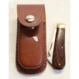 Pocket knife with brown wooden handle, in leather pouch
