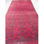 Large Afghan red ground rug, allover decorated with geometric medallions, 400cm x 205cm (A/F)