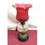 Early C20th oil lamp with cranberry etched shade, clear glass reservoir, on embossed brass base,