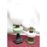 Early C20th oil lamp with opaque glass shade, opaline green tinted reservoir on cast metal base,