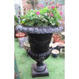 Large black painted cast iron garden urn with lion head handles and cherubs carrying a garland of