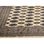 Bokhara pattern beige ground rug, field filled with stylized elephants foot medallions and stars