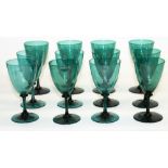 Set of twelve green glass wine glasses, bell shaped bowls on slender faceted stems and circular