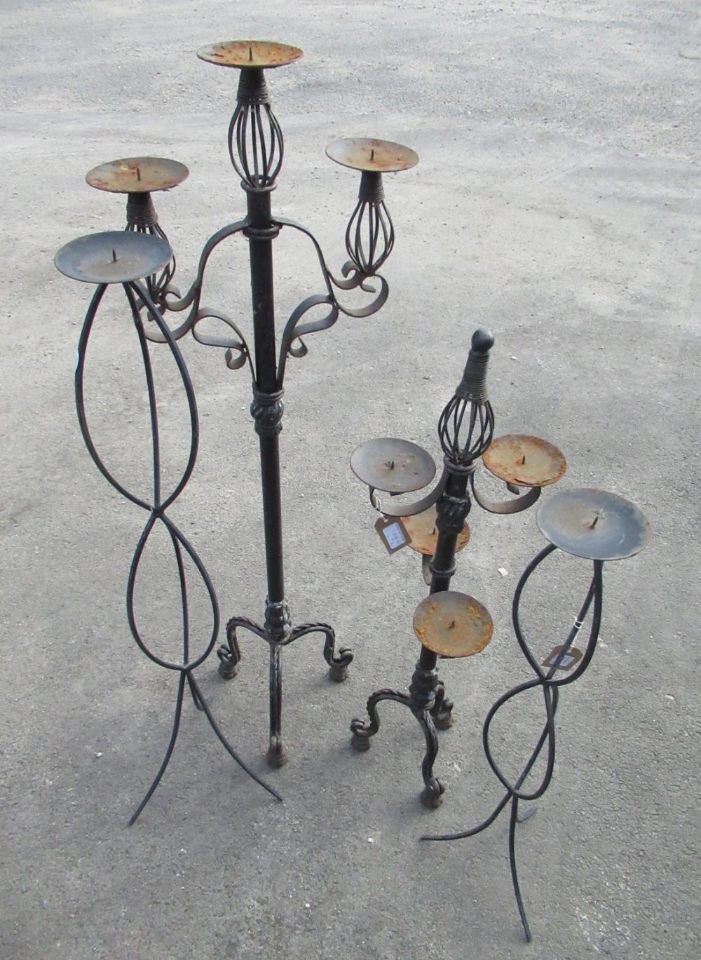 Graduated pair of black painted wrought metal tripod candlestands, on ropetwist supports, and a