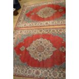 Pair of C20th Iranian wool rugs with central pattern medallion against red field, repeating fawn