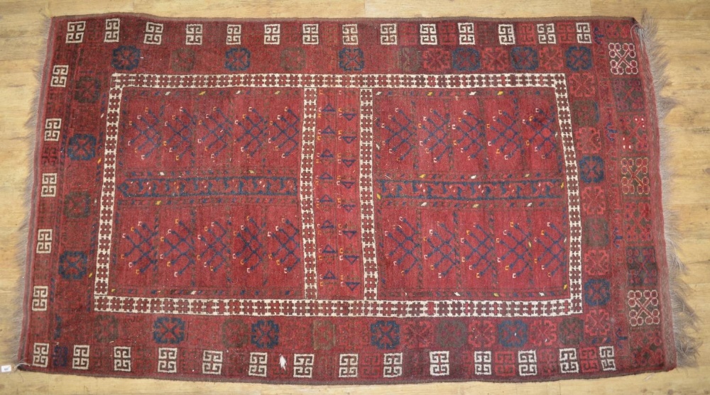 C20th Beshir style red ground wool rug, with patterned central field and geometric patterned border,