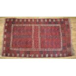 C20th Beshir style red ground wool rug, with patterned central field and geometric patterned border,