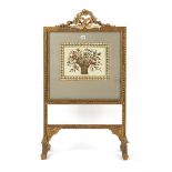 Property of a gentleman - a late Victorian gilt painted fire screen with floral needlework panel,