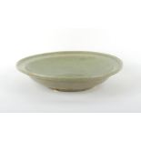 A large Chinese celadon glazed shallow dish, Ming Dynasty (1368-1644), 17ins. (43.2cms.) diameter.