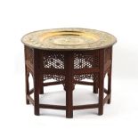 Property of a gentleman - a large Indian brass tray on carved & pierced hardwood octagonal folding