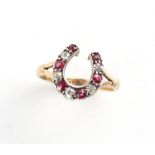 An unmarked late 19th / early 20th century yellow gold ruby & diamond horseshoe ring, size P/Q.