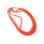 A coral three strand graduated bead necklace, the clasp stamped 750, the shortest strand 16.2ins. (