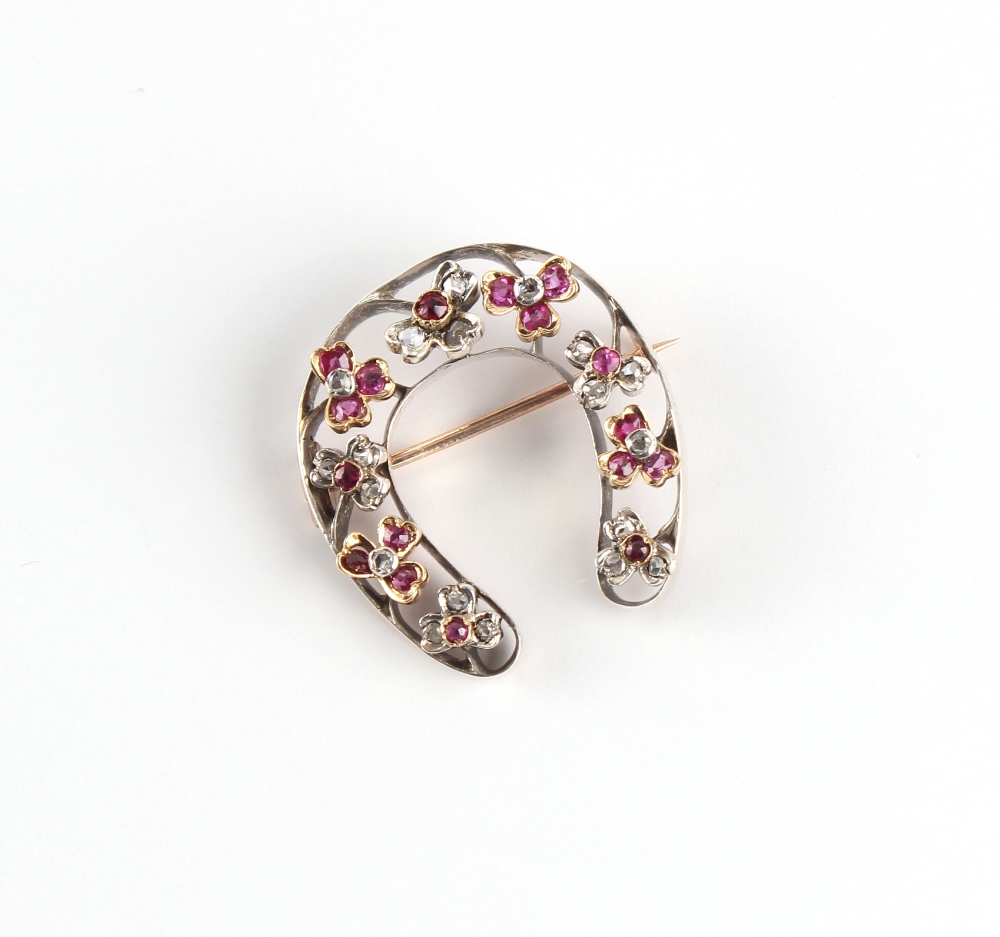 A Victorian unmarked rose gold ruby & diamond horseshoe brooch, 30mm long.