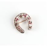 A Victorian unmarked rose gold ruby & diamond horseshoe brooch, 30mm long.