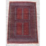 Property of a lady - a hand knotted wool Turkoman rug with square panels on a rust coloured