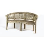 Property of a gentleman - a well weathered teak garden bench of curved outline, 63ins. (160cms.)