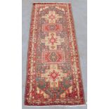 A Kordi woollen hand-made rug with red ground, 132 by 50ins. (335 by 127cms.).