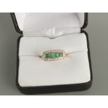 An early 20th century Art Deco unmarked yellow gold emerald & diamond ring, the five square cut