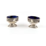 Property of a gentleman - a pair of George III silver oval pedestal salts, with blue glass liners,
