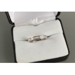 An unmarked platinum or white gold diamond eternity ring, set with alternating round brilliant cut &