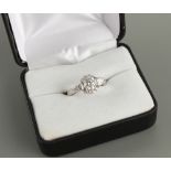 An unmarked platinum or white gold diamond ring, the centre round brilliant cut diamond weighing