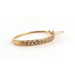 Property of a lady - a 9ct yellow gold hinged bangle set with round cut sapphires alternating with