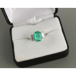 An Art Deco style unmarked platinum or white gold emerald & diamond ring, the octagonal cut